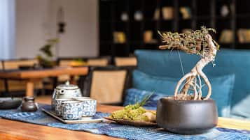 A traditional tea set on a table with a bonsai tree in a pot.
