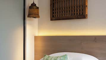 A hotel room with a bed, a hanging light fixture, and a wooden headboard.