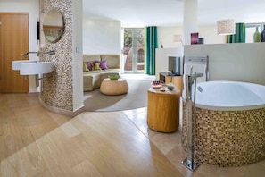 A modern bathroom with a large bathtub, a separate shower area, and a vanity with a mirror. - Scarlet Hotel (Newquay)