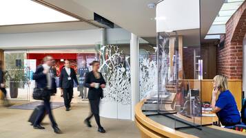 A modern lobby with a reception desk, glass partitions, and a staircase.