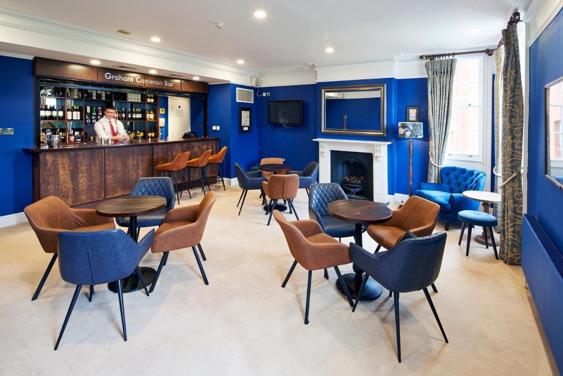 A bar area with a bartender, a fireplace, and seating arrangements.