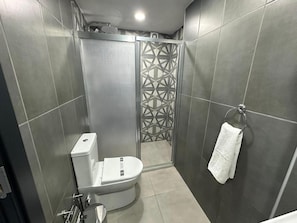 Moderni kylpyhuone, jossa on suihkukaappi, wc ja pyyhekoukku.