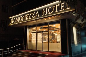 The exterior of the Monezza Hotel with a prominent illuminated sign, a glass entrance, and a red carpet leading to the entrance. - Monezza Hotel - Maltepe (Istanbul)