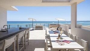 A sunlit outdoor dining area with a view of the ocean, featuring a bar, seating, and umbrellas. - Susurros del Corazon, Auberge Resorts Collection (Punta de Mita)