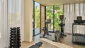 A modern gym with exercise equipment, large windows, and a view of greenery. - Susurros del Corazon, Auberge Resorts Collection (Punta de Mita)