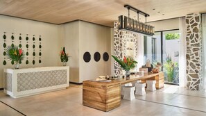 Una zona de recepción con un mostrador de madera, un muro decorativo de piedra y un amplio ventanal que ofrece vistas al exterior.