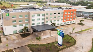 A Holiday Inn Express & Suites building with a modern design, featuring multiple floors, a covered entrance, and a parking area with a sign indicating the hotel. - Holiday Inn Express & Suites Diamond (Diamond)