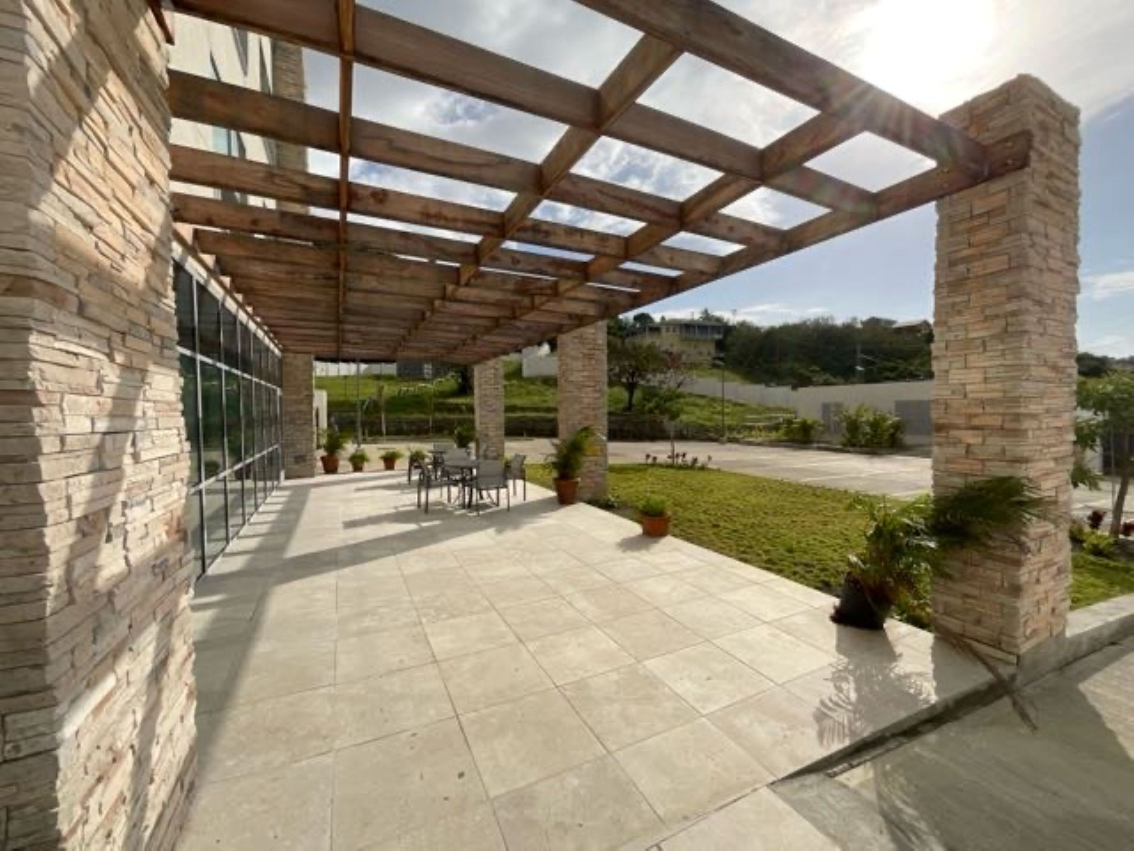 A covered patio area with stone walls, a pergola structure, and outdoor seating. - Holiday Inn Express & Suites Diamond (Diamond)