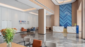 A modern hotel lobby with a reception desk, seating area, and a wall with the text 'EXPECT THE UNEXPECTED.' - Holiday Inn Express Nanning Convention and Exhibition (Nanning)