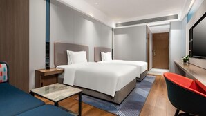 Habitación de hotel con dos camas, un escritorio, un televisor y una zona de estar.