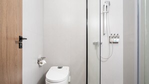Un baño moderno con inodoro, ducha y dispensador de papel higiénico.