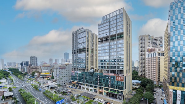 A multi-story hotel with a modern glass facade, located in a busy urban area with surrounding high-rise buildings. - Holiday Inn Express Nanning Convention and Exhibition (Nanning)