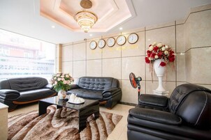 Uma sala de estar moderna com um sofá de couro preto, uma mesa de centro e um vaso decorativo com flores.