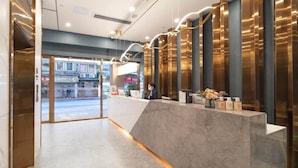 A hotel reception area with a marble floor, a reception desk, and a view of the street outside. - Cheermay Hotels (Guangzhou)