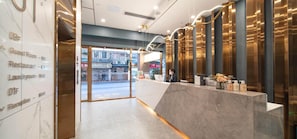 A hotel reception area with a marble floor, a reception desk, and a view of the street outside. - Cheermay Hotels (Guangzhou)