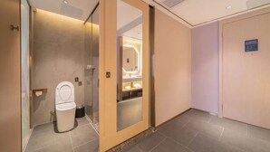 A modern bathroom with a toilet, a mirror, and a shelf with toiletries. - Cheermay Hotels (Guangzhou)