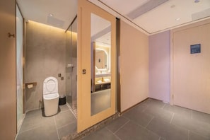 A modern bathroom with a toilet, a mirror, and a shelf with toiletries. - Cheermay Hotels (Guangzhou)