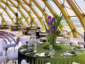 A dining area with round tables, chairs, and a central floral arrangement.