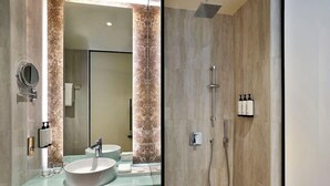 Een badkamer met een grote spiegel, twee wastafels, een douche en een handdoekhouder.