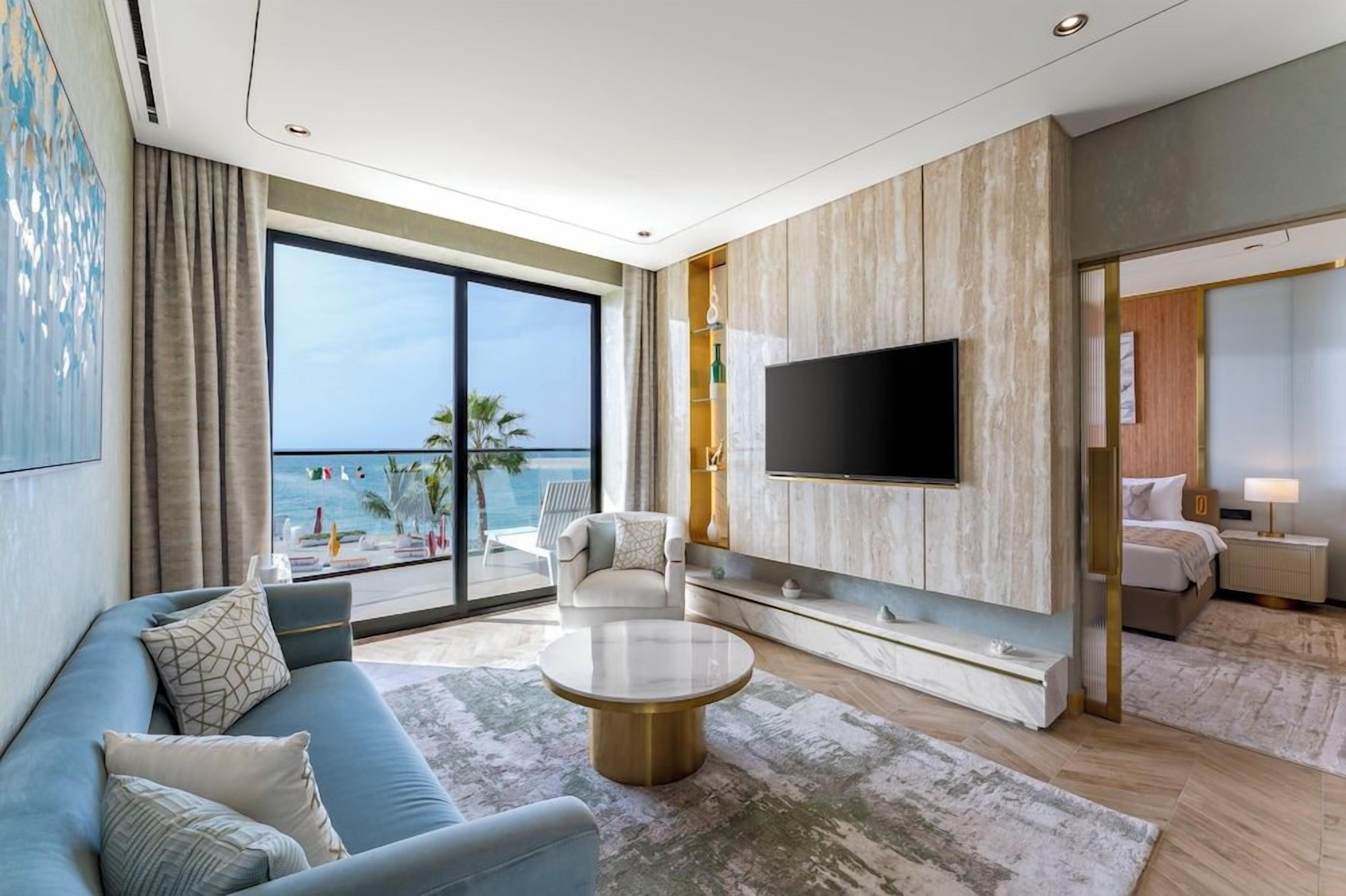 Ein modernes Hotelzimmer mit großem Balkon, einem Flachbildfernseher, einer Sitzecke und einem Couchtisch.