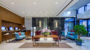 Eine moderne Lobby mit einer Rezeption, einer Sitzecke und einem großen Fenster.