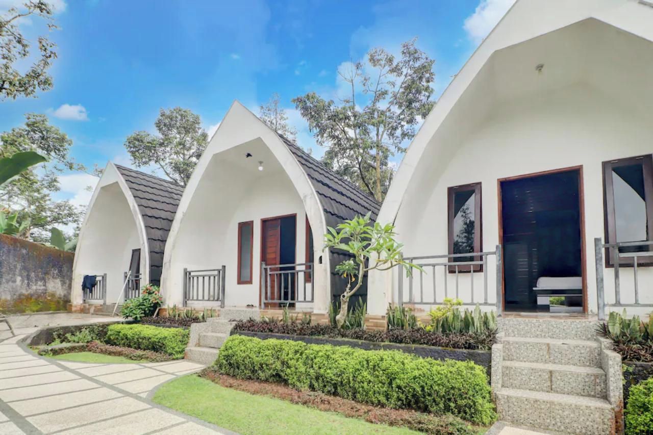 A row of white, arched-roofed buildings with a paved walkway and landscaped garden.