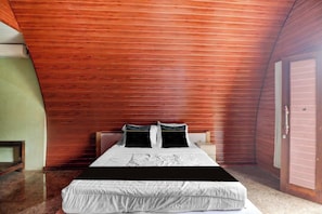 A bedroom with a wooden slatted ceiling, a bed with white bedding, and a wooden door.