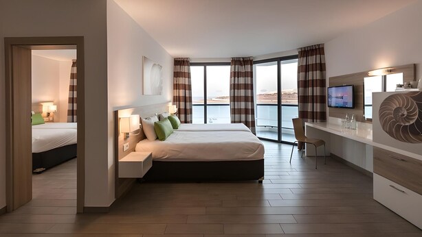 Una habitación de hotel moderna con cama, escritorio y ventanas amplias.