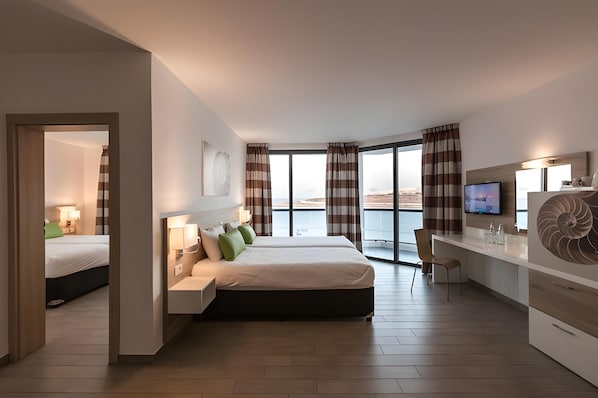 Une chambre d’hôtel moderne, équipée d’un lit, d’un bureau et de grandes fenêtres.