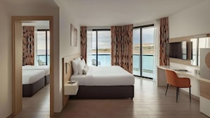 A modern hotel room with a large bed, a desk, and a TV. - AX Seashells Resort (St. Paul's Bay)