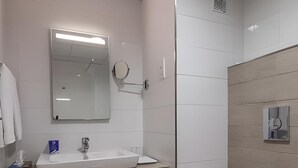Un baño moderno con lavabo, espejo y retrete blancos.