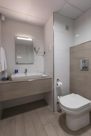 Une salle de bain moderne avec un lavabo blanc, un miroir et des toilettes.