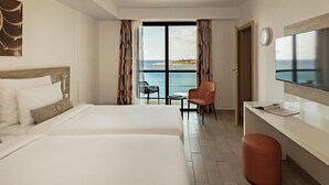 Habitación de hotel con dos camas, un escritorio, una silla y un televisor.