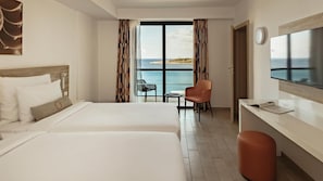 Habitació d'hotel amb dos llits, una taula de treball, una cadira i un televisor.