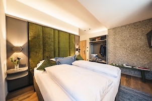 Un dormitorio moderno con cama, mesitas de noche, un armario y una pequeña zona de escritorio.