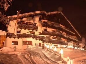 Un hotel de varios pisos con balcones, rodeado de nieve y un letrero que indica que es un hotel.
