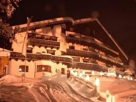 A multi-story hotel with balconies, snow-covered surroundings, and a sign indicating it is a hotel.