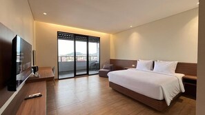 A modern hotel room with a large bed, a flat-screen TV, a sofa, and a balcony with a view. - Yes Hotel (Bandar Lampung)