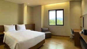 A modern hotel room with a large bed, a desk, and a chair. - Yes Hotel (Bandar Lampung)