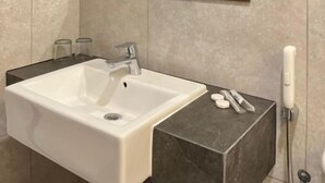 A bathroom with a white sink, a mirror, and a towel rack. - Yes Hotel (Bandar Lampung)