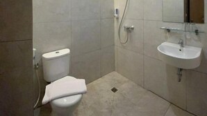 A modern bathroom with a toilet, shower, and sink. - Yes Hotel (Bandar Lampung)