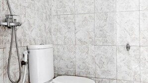 Une salle de bain avec des toilettes, une douche et un mur en marbre.