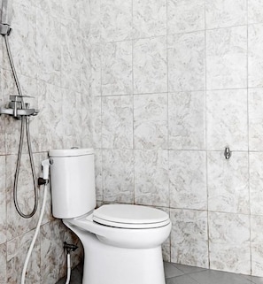 Un baño con inodoro, ducha y pared de mármol.