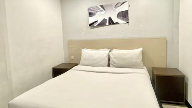 Une chambre d’hôtel comprenant un lit, deux tables de chevet et une œuvre d’art accrochée au mur.