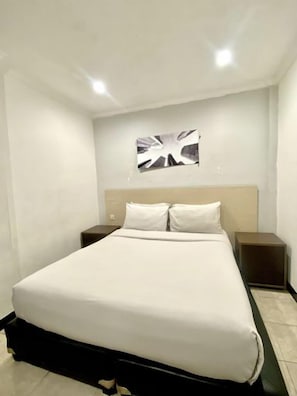 Una habitación de hotel con una cama, dos mesitas de noche y una obra de arte colgada en la pared.