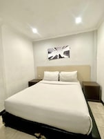 A hotel room with a bed, two bedside tables, and a wall-mounted artwork.