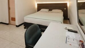 Une chambre d’hôtel avec un lit, un bureau, une chaise et un miroir.