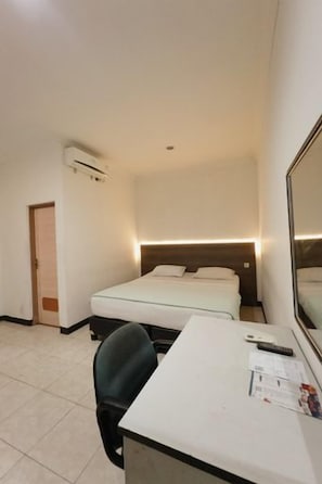 Habitación de hotel con cama, escritorio, silla y espejo.