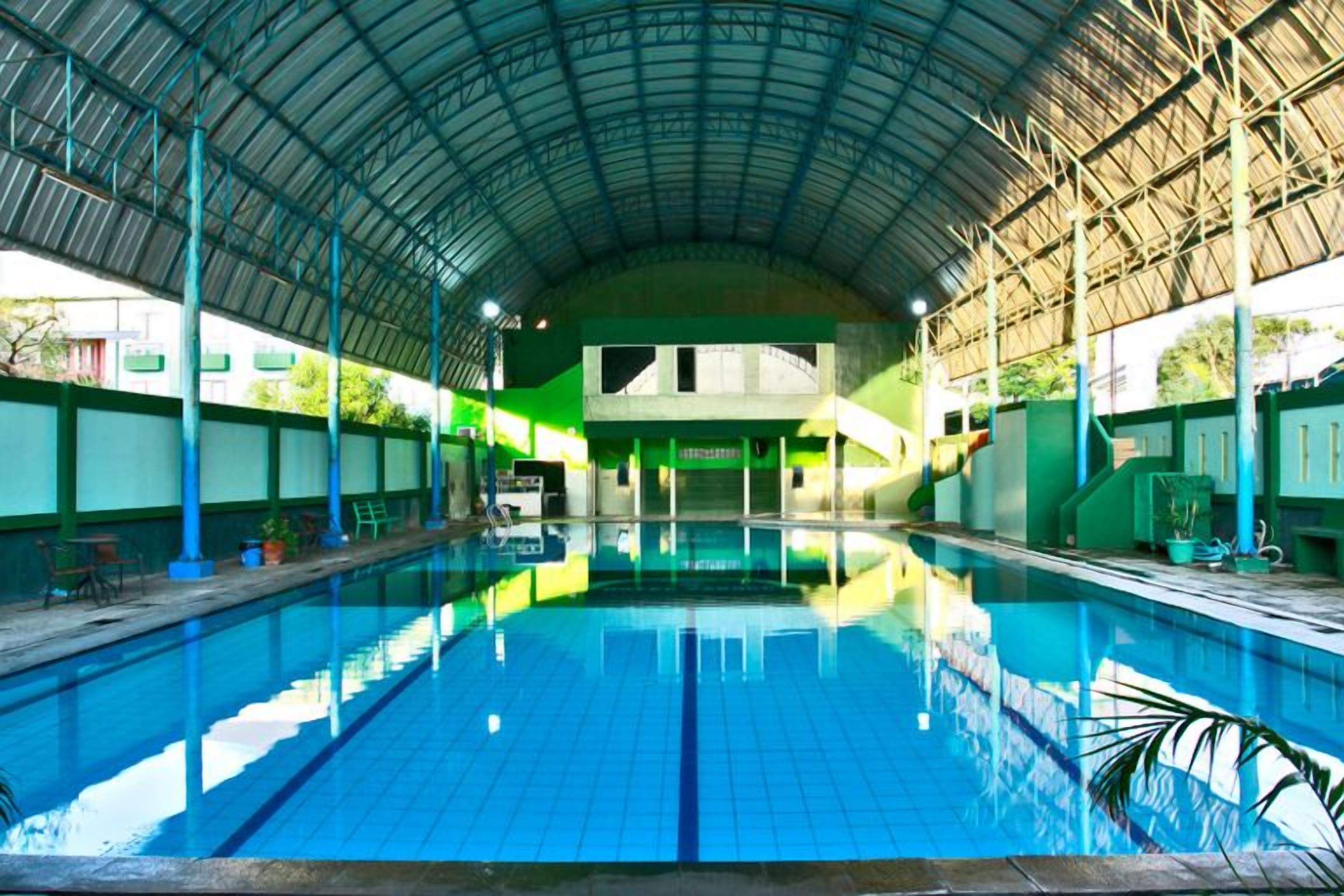 Une piscine intérieure avec un plafond haut et des murs carrelés.