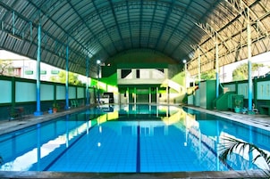 An indoor swimming pool with a high ceiling and tiled walls.